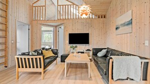 A wooden interior with a TV, two sofas, a coffee table, and a hanging light fixture. - Beautiful home in Idestrup with sauna (Idestrup)