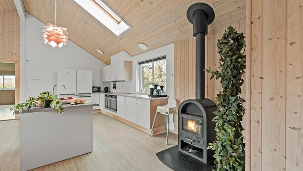 A modern kitchen with a central island, a built-in wood stove, and a skylight. - Beautiful home in Idestrup with sauna (Idestrup)