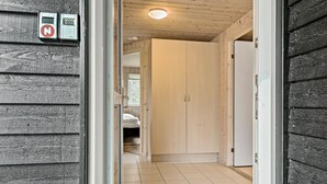 A hallway with a wooden door, a white refrigerator, and a tiled floor. - Beautiful home in Idestrup with sauna (Idestrup)