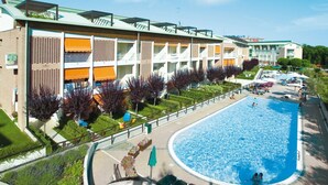 A modern hotel with a swimming pool, outdoor seating, and a well-maintained garden.