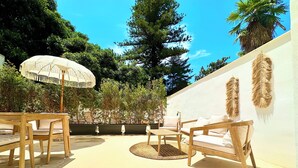 An outdoor patio with wooden furniture, a round table, and a large umbrella.