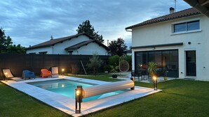 A backyard with a swimming pool, outdoor seating, and a house with large windows. - Maison d Isaure (Bergerac)