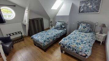 Une chambre avec deux lits, une fenêtre, un radiateur, une chaise et un tableau accroché au mur.
