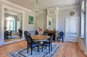 Uma sala de jantar com mesa redonda, cadeiras, lustre e lareira.