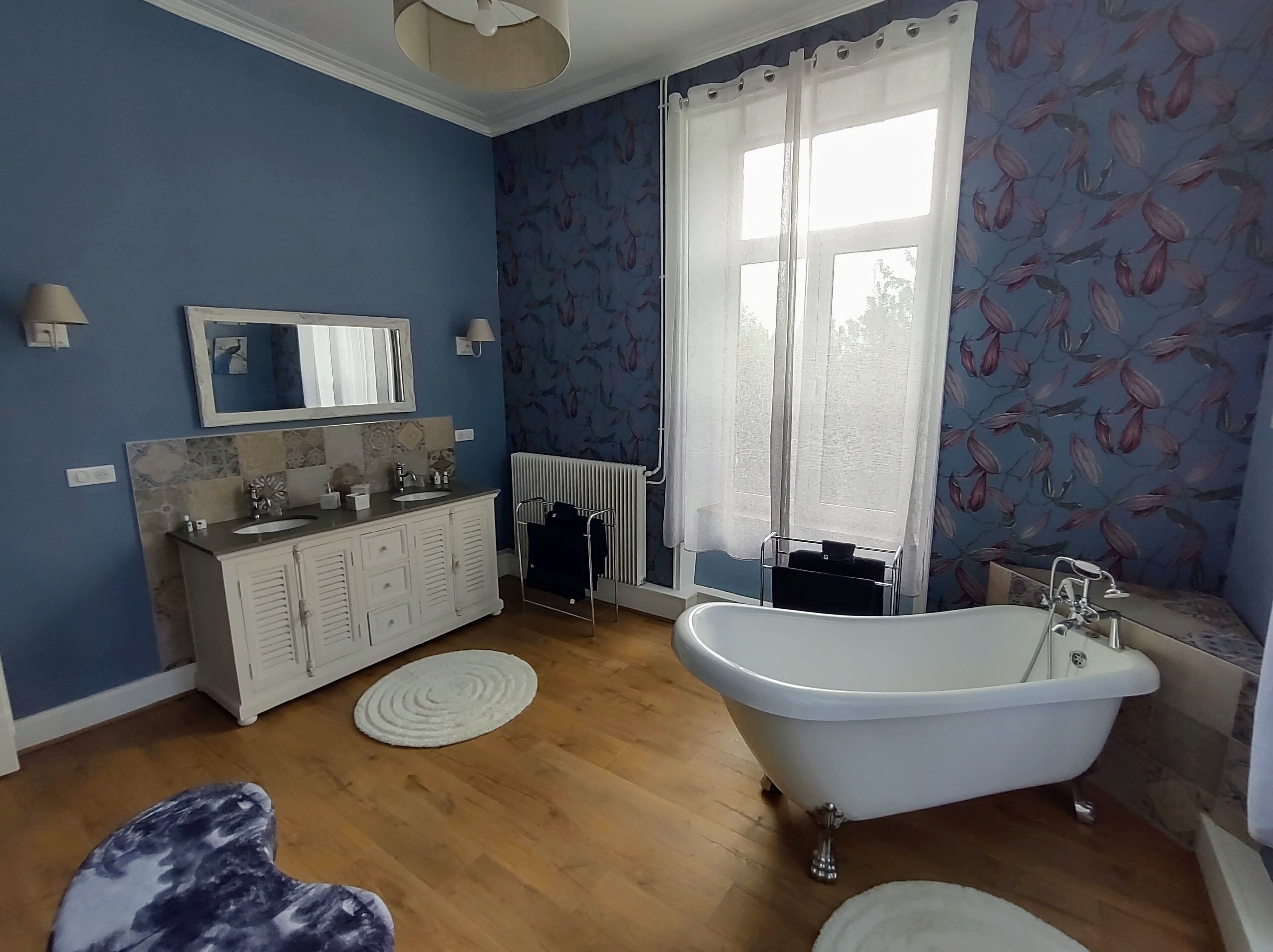 Une salle de bain avec une baignoire sur pieds, un meuble-lavabo avec un miroir et un radiateur.