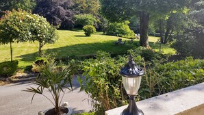 Een tuin met gazon, bomen en een lantaarnpaal.