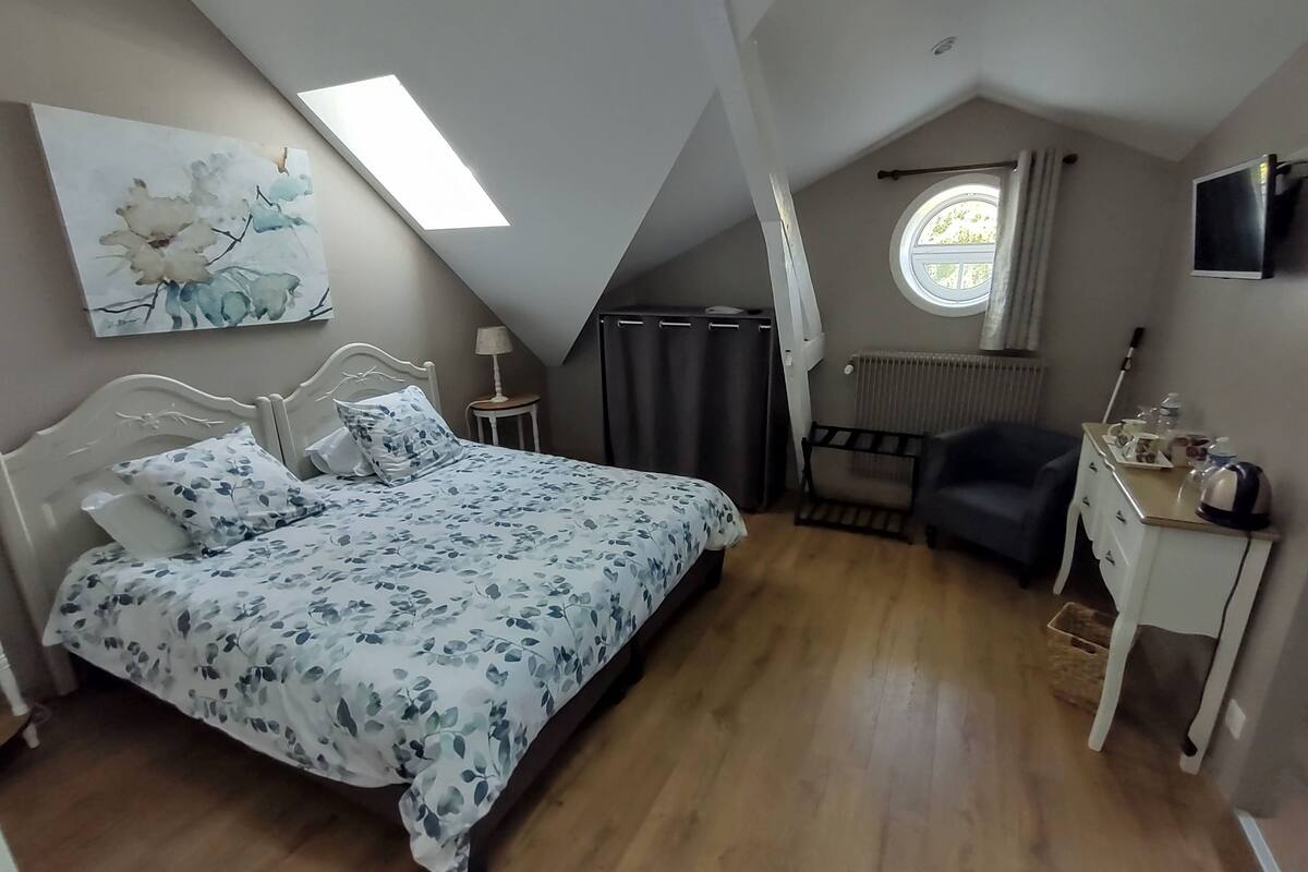 Une chambre à coucher comprenant un lit, un bureau, une chaise, un radiateur, une télévision et une lucarne.