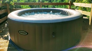 Een jacuzzi met een houten terras en een houten hek op de achtergrond.