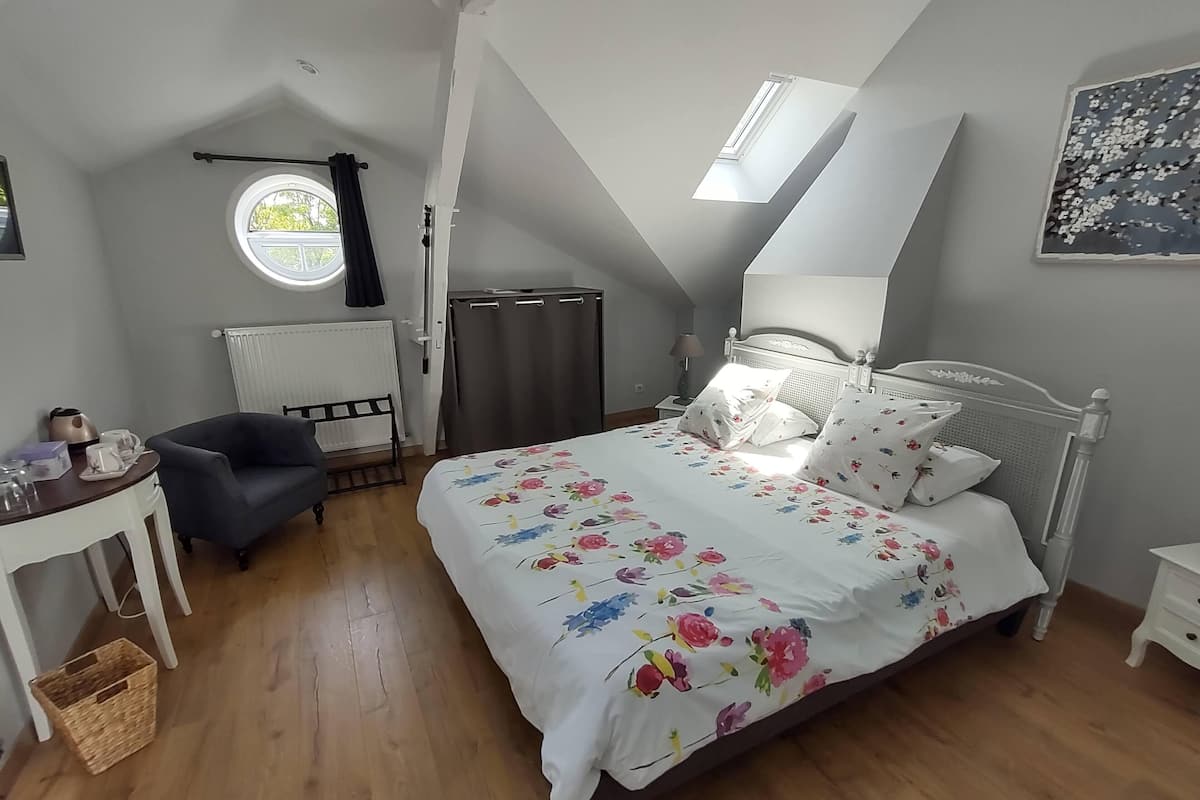 Une chambre à coucher comprenant un lit, une chaise, une table, un radiateur, une fenêtre et un luminaire au plafond.