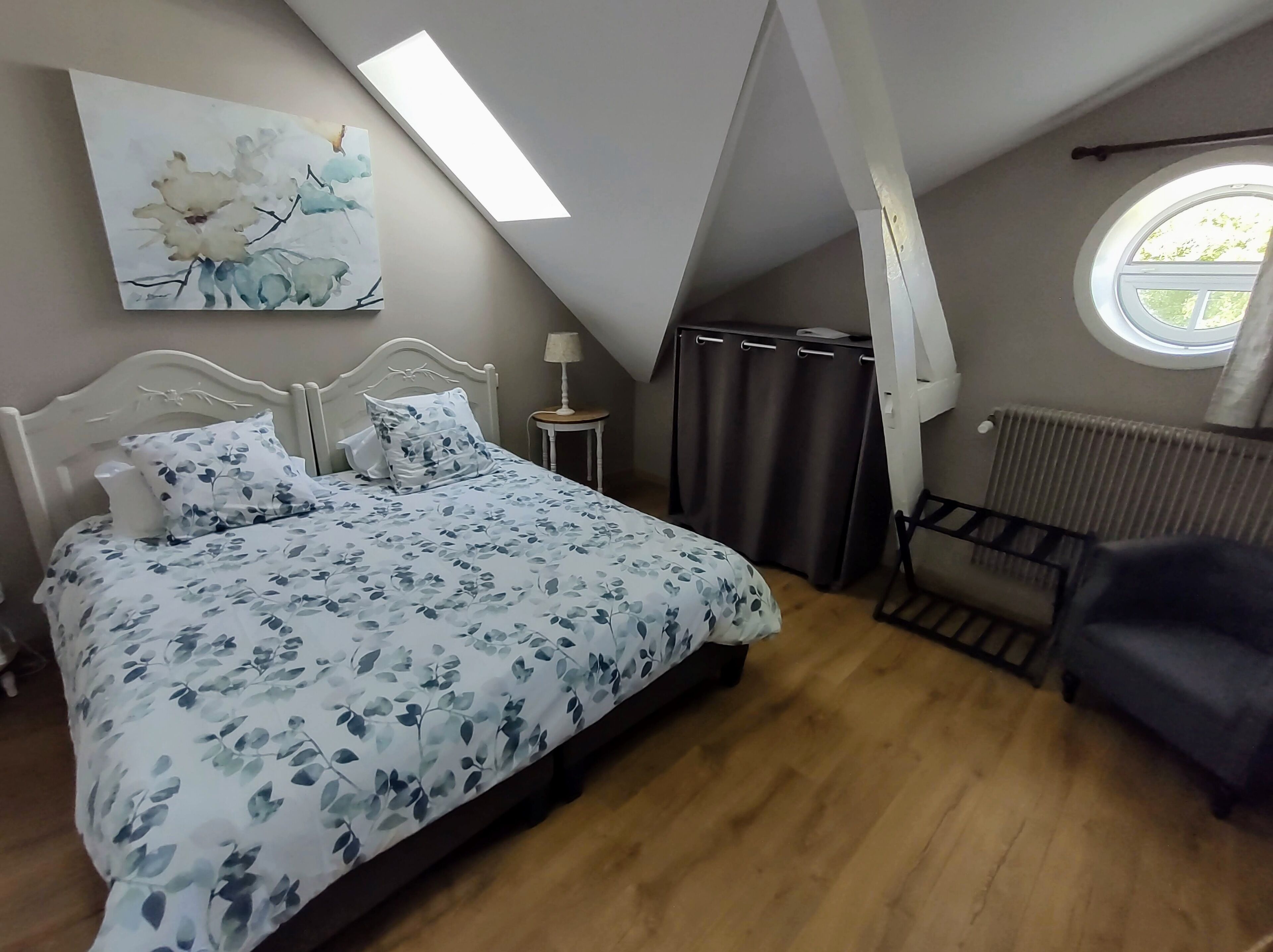 Een slaapkamer met een bed, nachtkastje, lamp, raam en radiator.