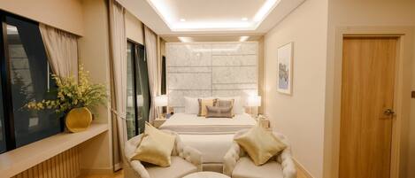A modern hotel room with a large bed, bedside lamps, a seating area with a coffee table, and a view through a window with curtains.