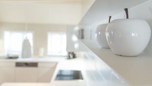 Una cucina moderna con mobili bianchi, un piano di lavoro bianco e un lampadario.
