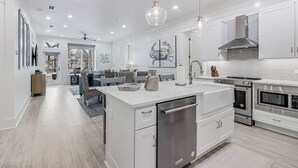 Una cocina moderna con armarios blancos, electrodomésticos de acero inoxidable y una isla central con lavavajillas.