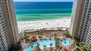 A high-rise hotel with a beach view, a swimming pool, and a beach area with people. - Shores of Panama by Blue Swell (Panama City Beach)
