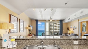A kitchen with granite countertops, stainless steel sinks, and a ceiling fan. - Shores of Panama by Blue Swell (Panama City Beach)