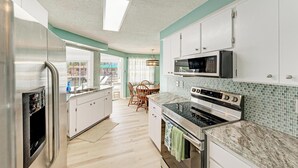 A modern kitchen with white cabinets, a stainless steel refrigerator, a microwave, and an oven. - Hometown Paradise- Canalfront home with dock and heated pool  (Bradenton)