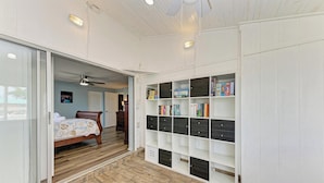 A bedroom with a bed, a sliding door leading to a balcony, a ceiling fan, and a built-in bookshelf. - Hometown Paradise- Canalfront home with dock and heated pool  (Bradenton)