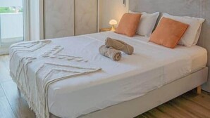 A bedroom with a large bed, a ceiling light, an air conditioning unit, and a view through a sliding door. - Bel Appartement vue mer - Mafat'appart (La Possession)