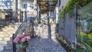 A courtyard with a marble staircase, a wrought iron railing, a planter with pink flowers, and a mural on the wall. - Thanh Do 1 Hotel (Xuan Huong - Da Lat)
