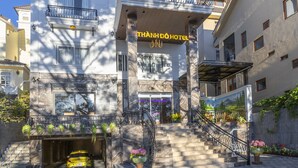 A multi-story hotel with a prominent entrance, a balcony with railings, and a sign indicating it is a hotel. - Thanh Do 1 Hotel (Xuan Huong - Da Lat)