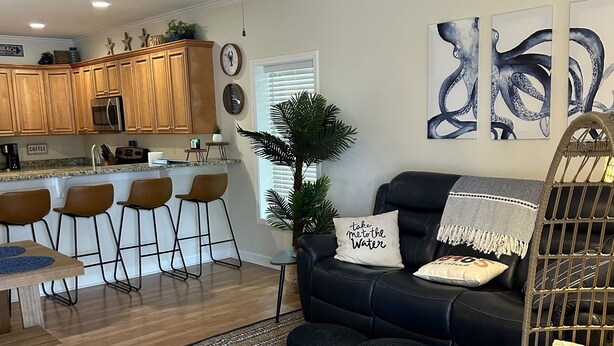 Ein modernes Wohnzimmer mit einem dunkelgrauen Sofa, einem Couchtisch und einem Essbereich mit Holzkohlen.