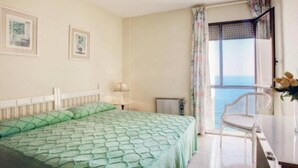 Un dormitorio con cama, una silla, una mesa y una ventana con vistas.
