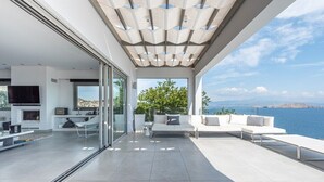 Un'ampia zona giorno moderna e open space con una grande vetrata che dà su un balcone con vista sull'acqua.