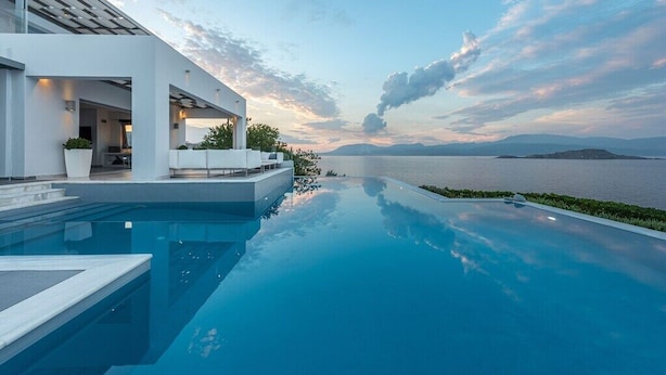 Una piscina a sfioro moderna con vista sul mare e sulle montagne.