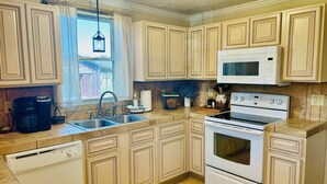 A kitchen with beige cabinets, a white microwave, a stove, a coffee maker, and a sink. - Minutes from Shorter University, Berry College, Tennis Center and Rome Area. (Armuchee)