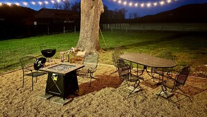 An outdoor patio area with a metal table and chairs, a barbecue grill, and string lights. - Minutes from Shorter University, Berry College, Tennis Center and Rome Area. (Armuchee)
