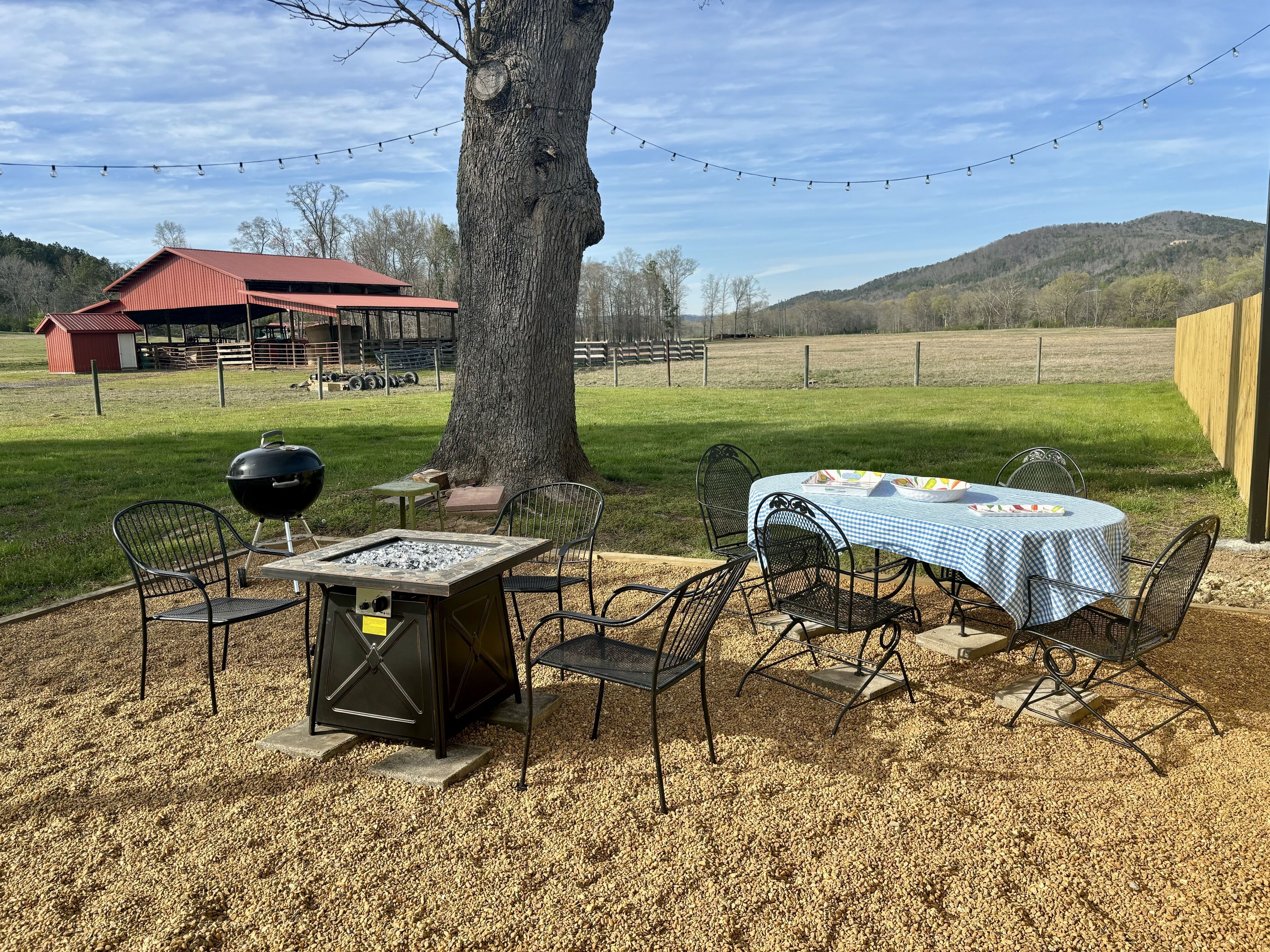 An outdoor patio with a grill, seating, and a table set for dining.