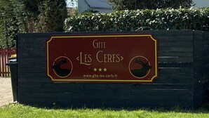 En skylt för ”Gîte Les Cerfs” med en webbadress och en logotyp som föreställer en hjort.