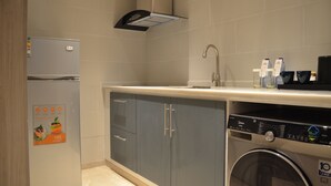 A compact kitchen with a built-in washing machine, a refrigerator, and a sink.
