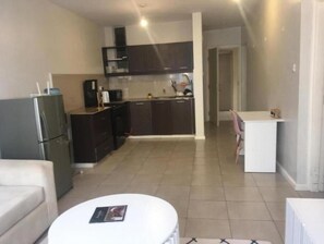 Cozy living space with a kitchenette, sofa, and table, perfect for compact stays.