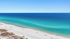 A beach with clear turquoise waters and a sandy shore. - Beach Vibes, Beachfront Penthouse, Pelican Beach Resort (Destin)