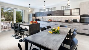 Une cuisine moderne avec un coin repas, comprenant un grand îlot central, des tabourets de bar et une table dressée pour le repas.