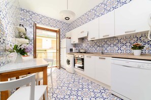 Une cuisine avec des meubles blancs, un lave-linge, un four Ă micro-ondes et un lave-vaisselle Bosch.