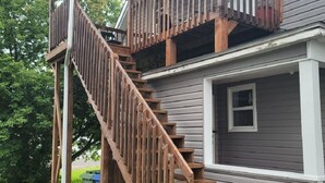 Une maison à deux étages avec un escalier en bois menant à un balcon.
