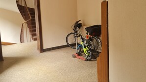 Une pièce dont le sol est recouvert d’une moquette, qui possède un chambranle de porte en bois et où l’on aperçoit un escalier au fond.