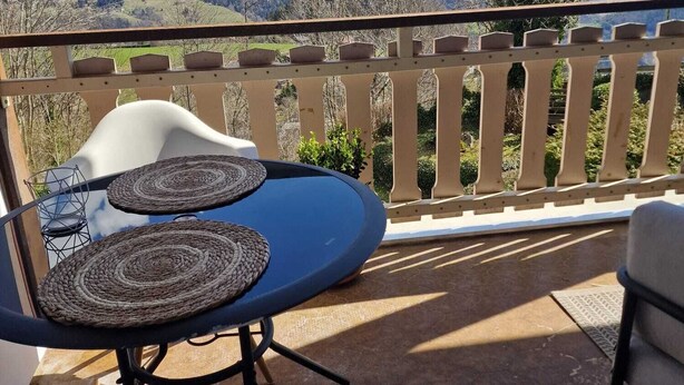 Un balcon avec une table et des chaises, donnant sur un paysage montagneux.