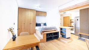 Une chambre compacte et moderne, équipée d’un lit, d’un petit coin cuisine et d’une table à manger.
