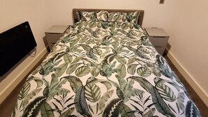 A bedroom with a bed, a TV, and a nightstand.