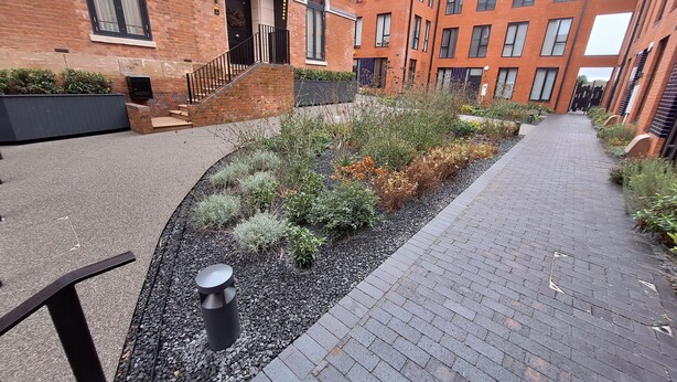 A courtyard with a brick building, a pathway, and a small garden area.