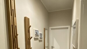 Ein Flur mit einer hölzernen Bank, einer an der Wand befestigten Holzkonstruktion und einer Tür am Ende.