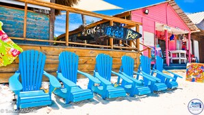 A beach bar with a sign reading "Beach Bar" and several blue Adirondack chairs lined up outside. - Beautiful 2-bedroom 3rd level condo with private rooftop terrace  (Punta Cana)
