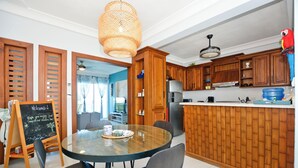A modern kitchen with wooden cabinets, a round glass table, and black chairs. - Beautiful 2-bedroom 3rd level condo with private rooftop terrace  (Punta Cana)