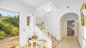 A spacious hallway with a white staircase, a small table with a chair, and a basket. - Villa Quinta Marta Luisa by Villa Plus (Silves)