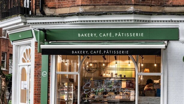 Una panetteria, un caffè e una pasticceria con un tendone verde e una porta bianca.