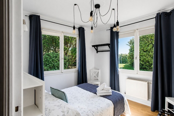 A bedroom with a bed, a chair, a desk, and large windows with curtains. - Dune & Sea Panoramic Views 4★ Walk to Beach & Town (Le Touquet Paris Plage)