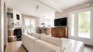 Ein modernes Wohnzimmer mit Kamin, Fernseher und großem Fenster.